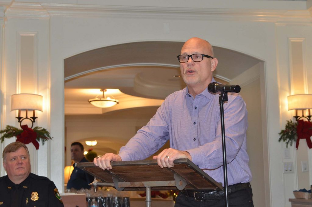 Man in a purple shirt speaking at a law enforcement banquet