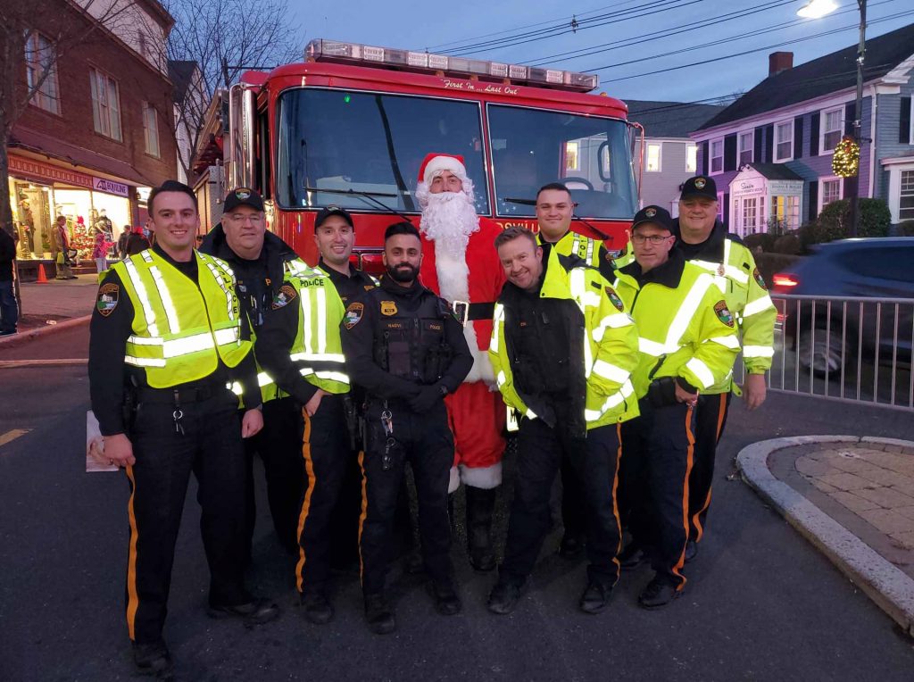 Members of the Bernardville Law Enforcement team posing with a man dressed as Santa Claus in front of a fire truck